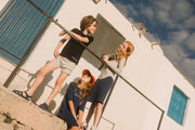 boy wearing grey track shorts and black tee hanging out with two other little girls