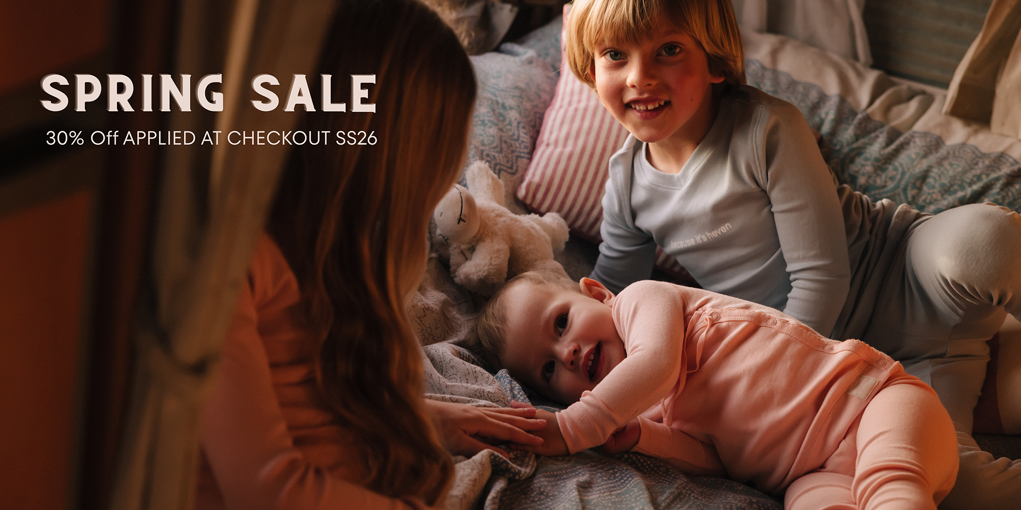 Children playing on a bed, promotional text for a spring sale.