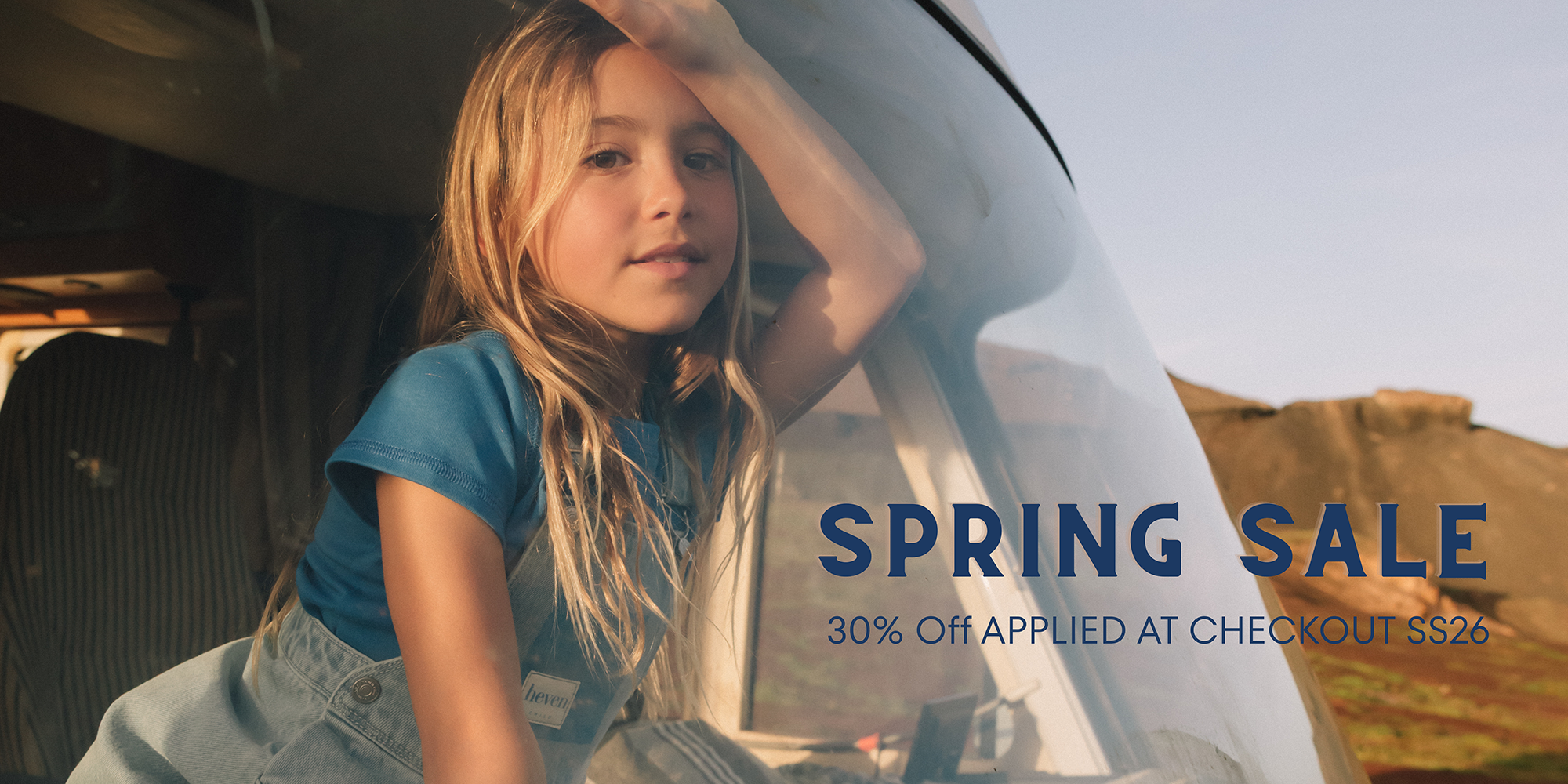 Girl sitting in a car near a mountain, sales announcement.