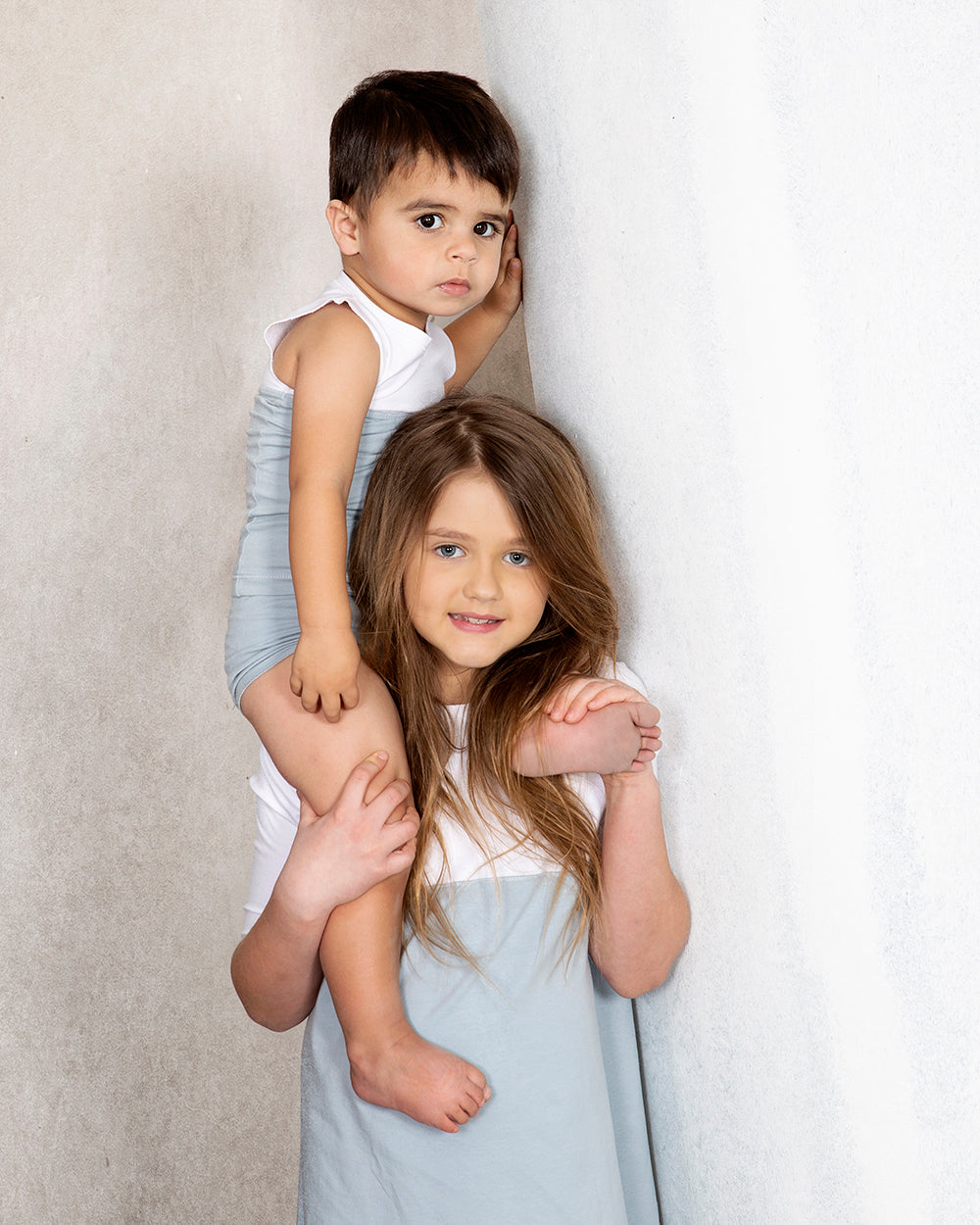 Toddler sitting on a young girls shoulders wearing a color block tank top and matching light blue shorts