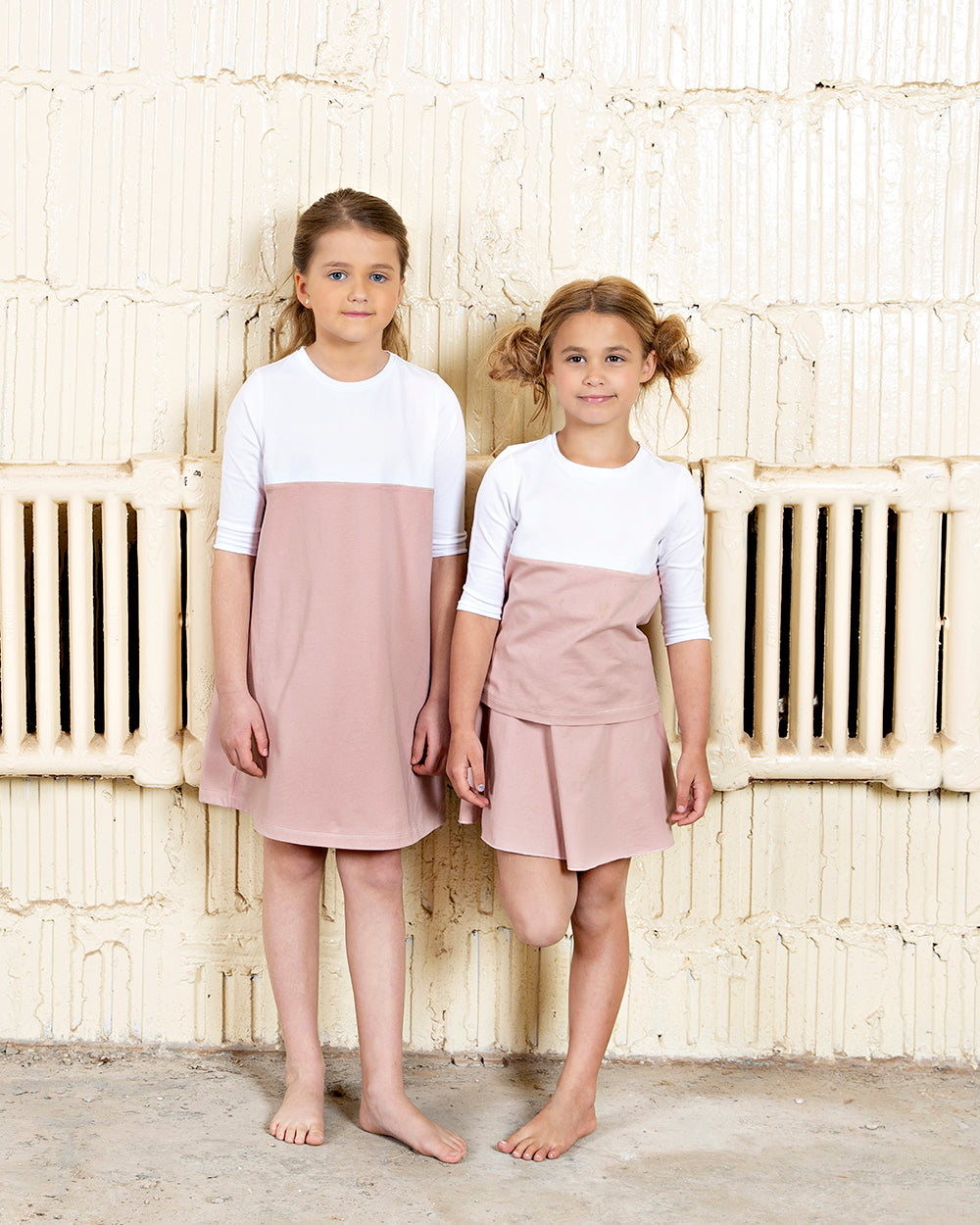 two young girls, one wearing color block pink and white dress, the other wearing color block tee and skirt
