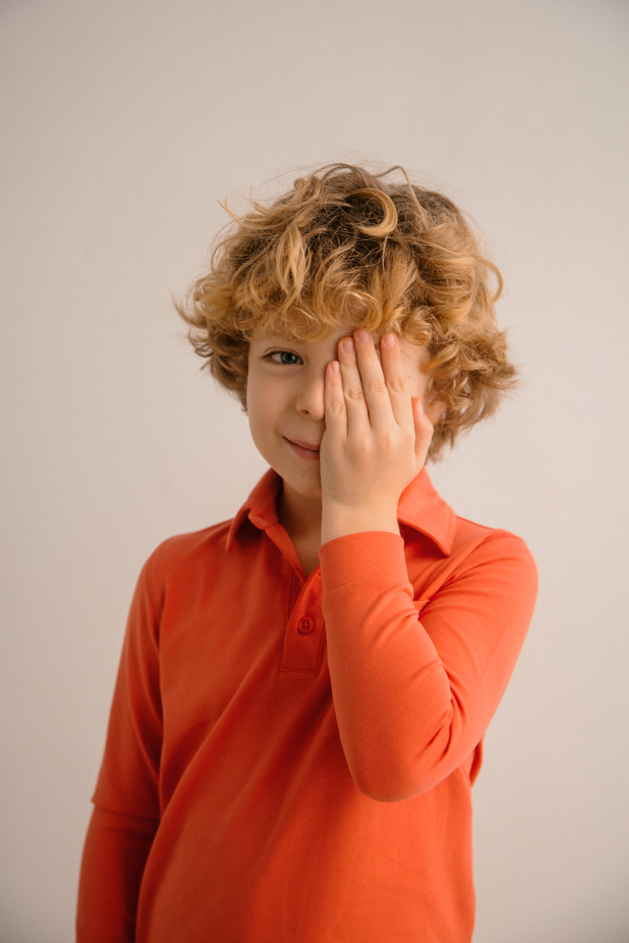 Child wearing an orange shirt with a plain background