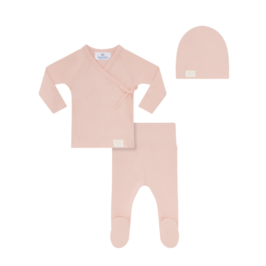 Pink baby outfit set with a onesie, long-sleeve shirt, and hat on a white background