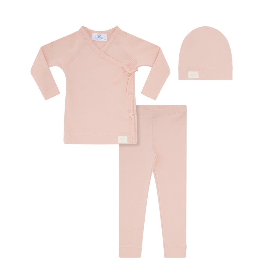 Pink baby outfit set with top, pants, and hat on a white background