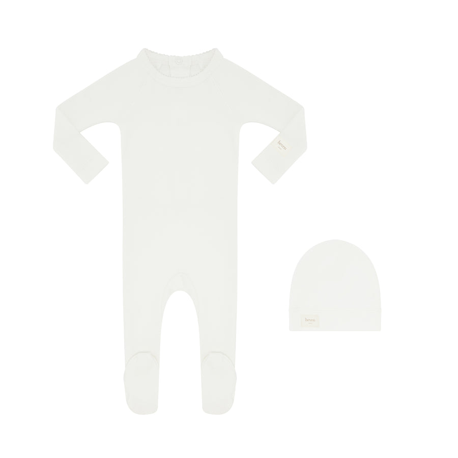Ivory baby footie and matching beanie on a white background.