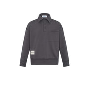 A dark gray long-sleeve polo shirt with a buttoned collar, a chest pocket, and a small beige brand patch on the lower left sleeve, shown against a plain white background.