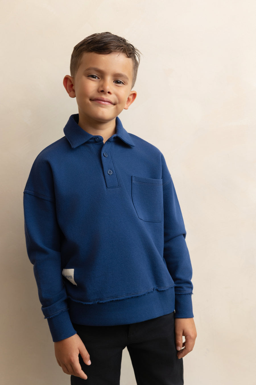 Child wearing a blue sweater with a collar on a beige background