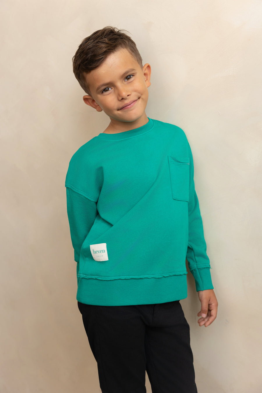 Child wearing a teal sweater with a plain background