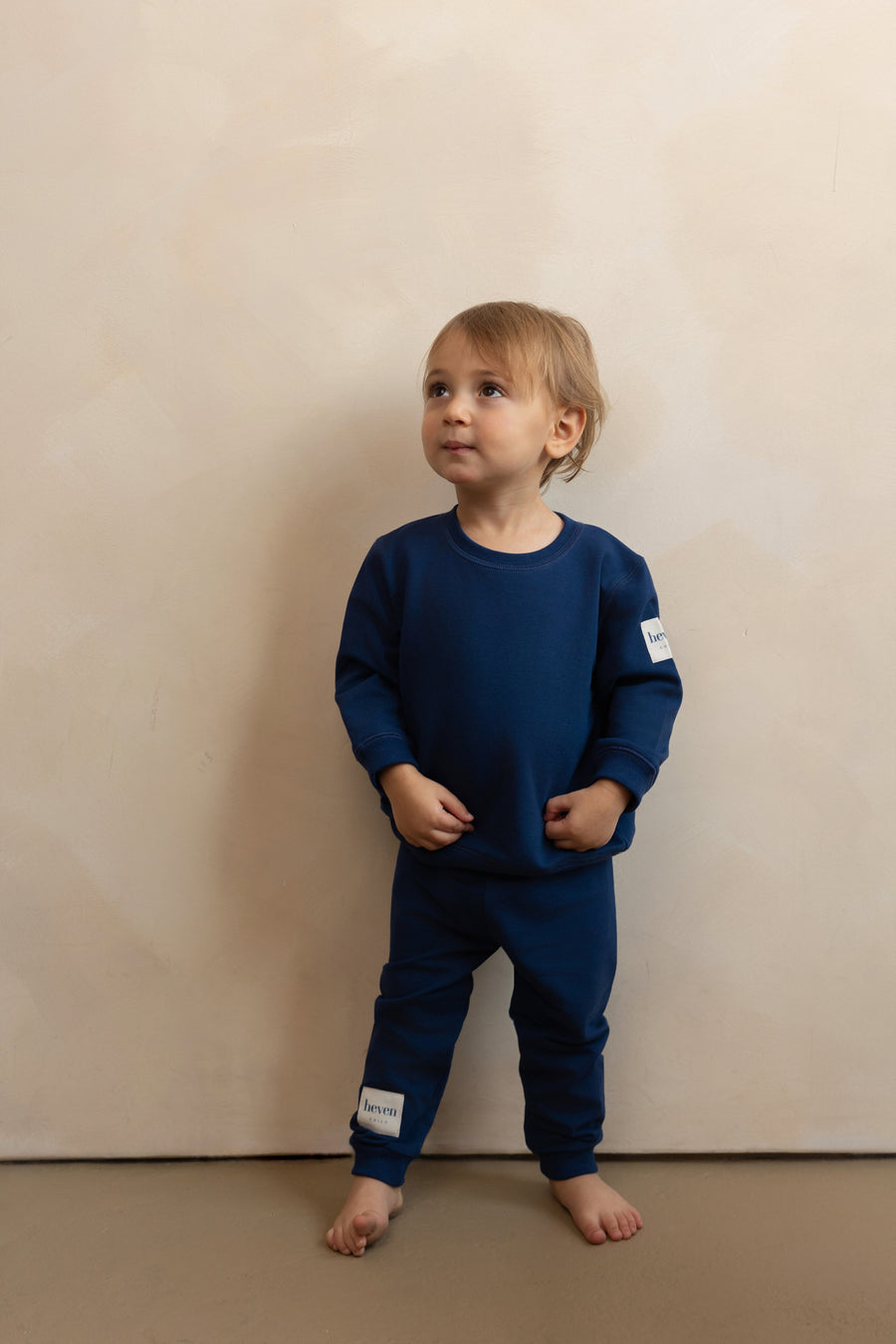 Child wearing a navy blue outfit with patches on a beige background