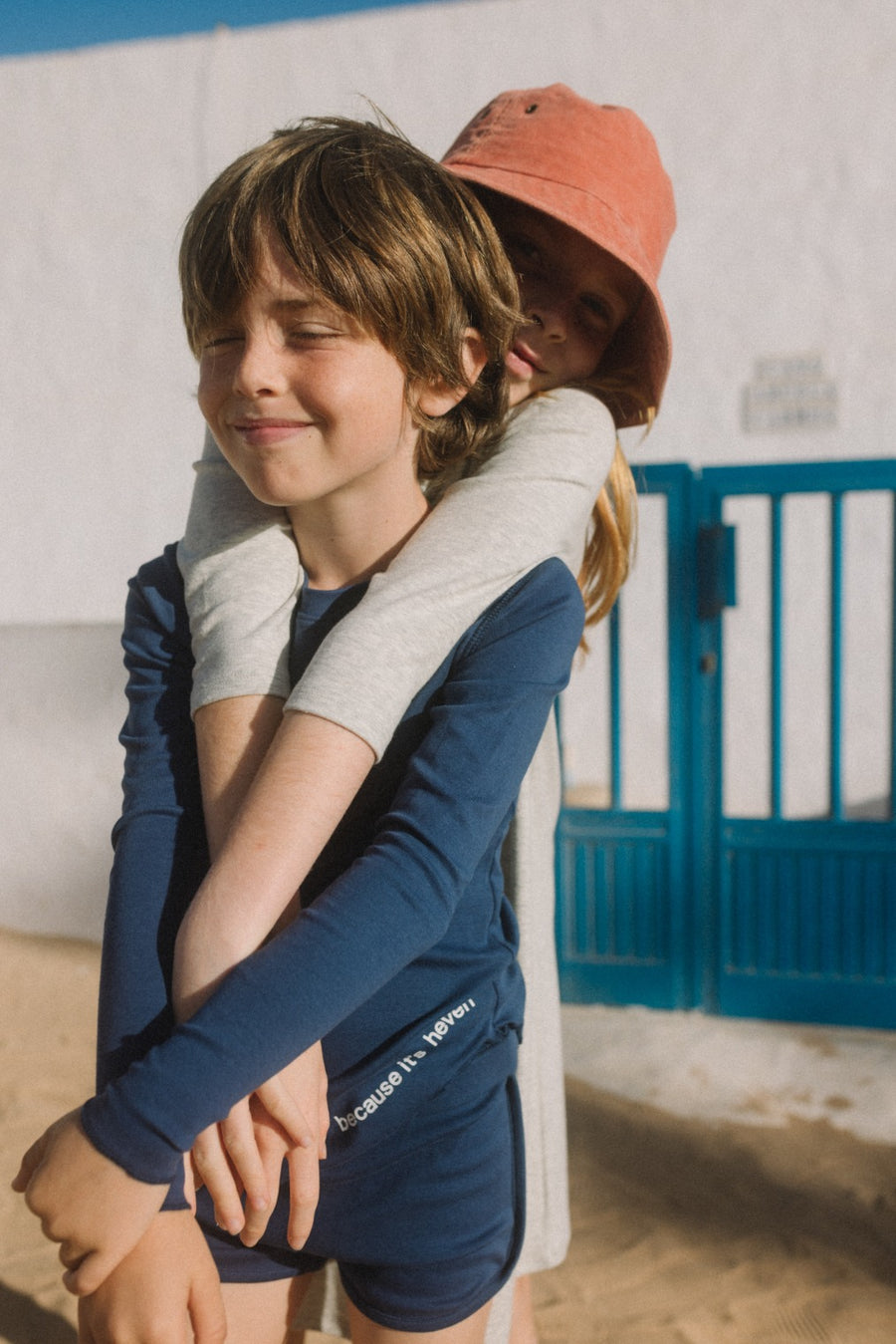 kid wearing long sleeve T-Shirt and a friend hugging her from behind