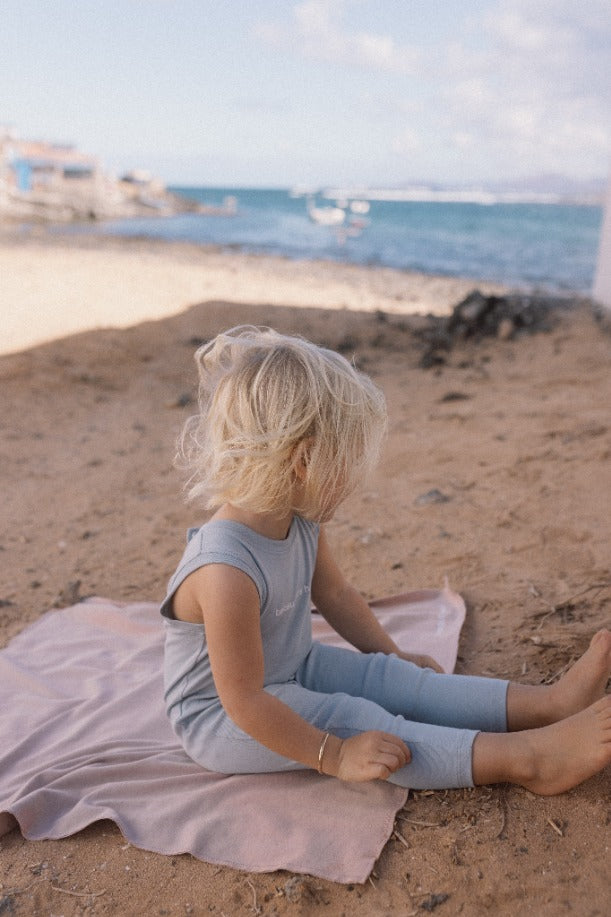 blond girl on the beach wearing the light blue baby romper