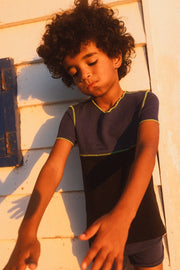 boy with curly hair wearing a blue and black short sleeve T-shirt