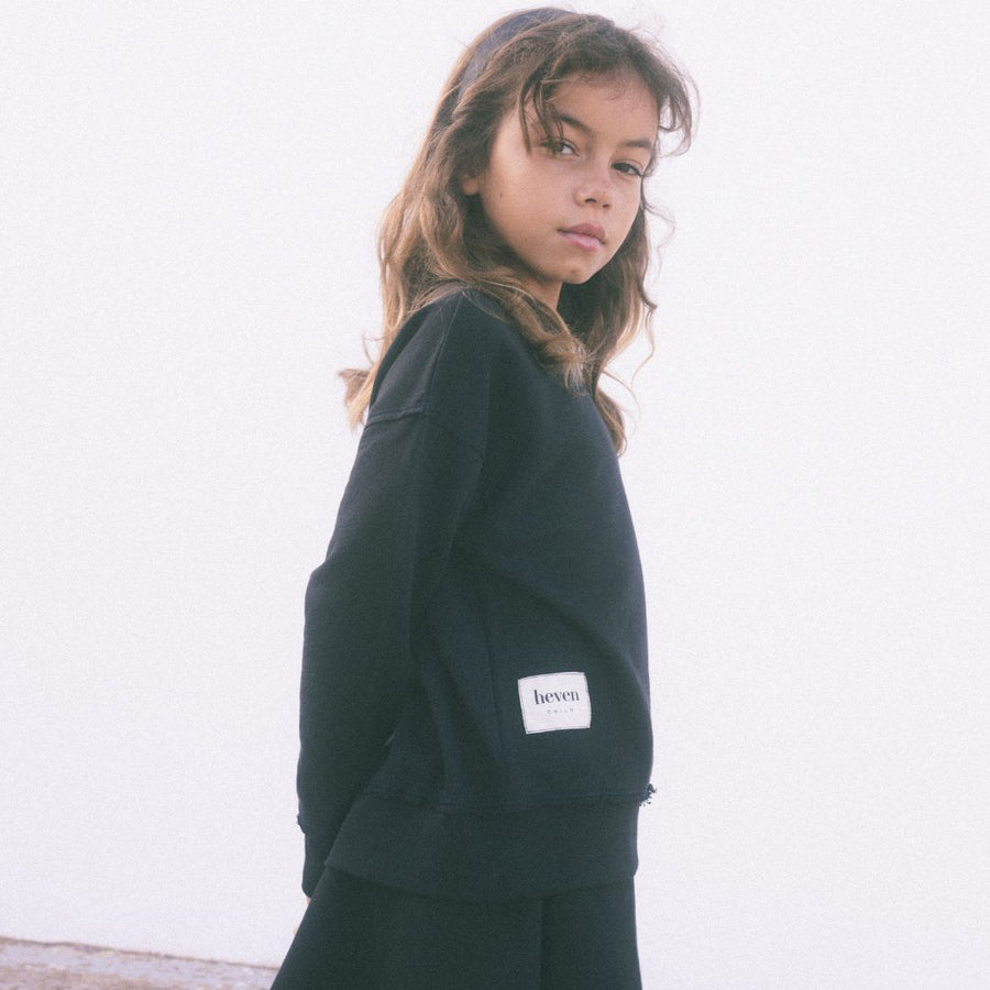 Girl wearing black sweatshirt with heven logo