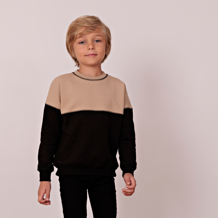 Young boy wearing tan and black color block sweatshirt